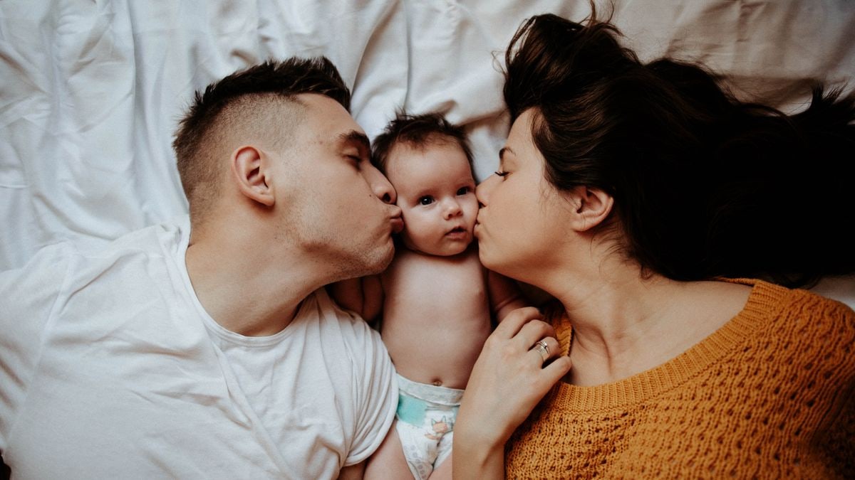 Parents lovingly kiss their newborn baby, showcasing tender family bonds.